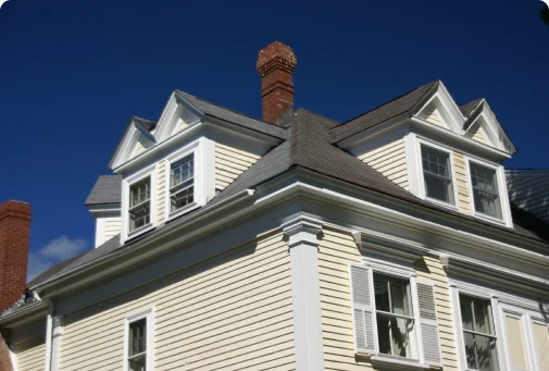 A white house with a brown roof and two chimneys